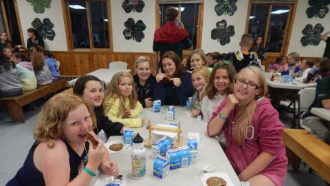Cabin group huddled together at a table smiling at the camera.