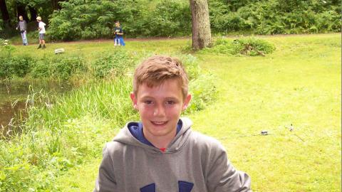 Youth holding a fish they caught.