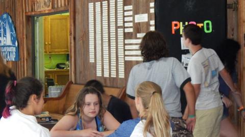 Campers seated at a table as counselor enters darkroom.