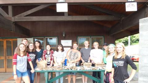 Large group of counselor in training youth at picnic table with popsicles for snack.
