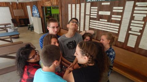 Youth holding hands and smiling as they try to unknot themselves.