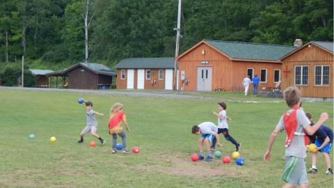 Youth scrambling to grab balls at the start of a dodgeball game.