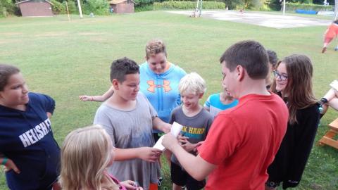 Group of youth surround a counselor and give them a paper.