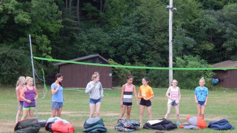 Cabin group standing together each behind a sleeping bag.