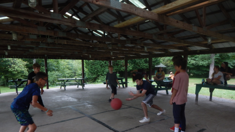 Youth in the rec hall playing four square.