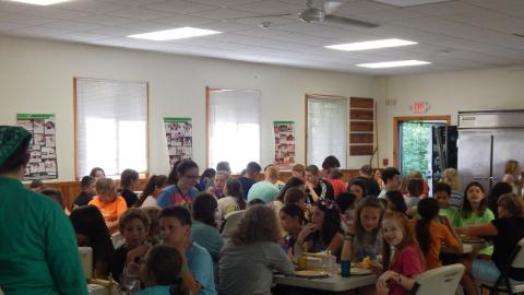 Campers and counselors seated together for a family style meal.