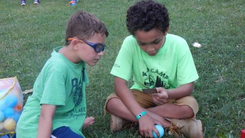 Two youth seated on ground looking at a Magic Card.
