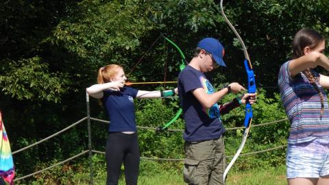 Youth on shooting line drawing their bows.
