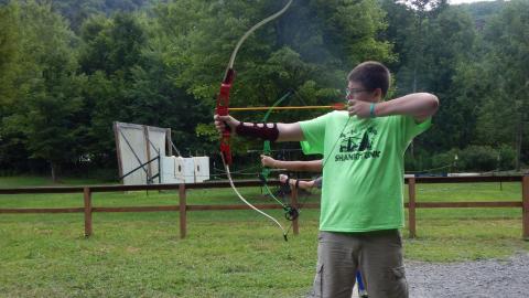 Youth stand on the line, bows drawn, ready to fire.