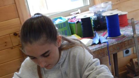 Camper stringing beads according to a tweedie bird pattern in front of them.