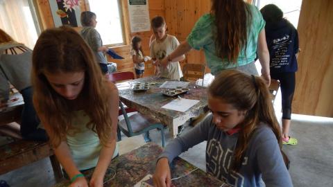 Campers string beads according to an ice cream cone pattern in front of them.