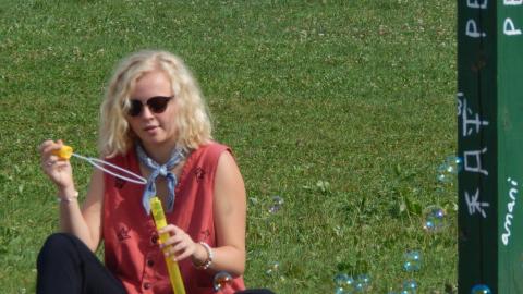 Youth sitting and blowing bubbles near peace pole.