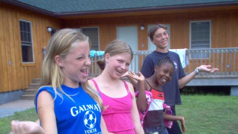 Four youth making smiling faces and waving their hands looking into the camera