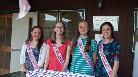 Four dairy ambassadors at the table in front of Rice Hall with many cartons of milk.