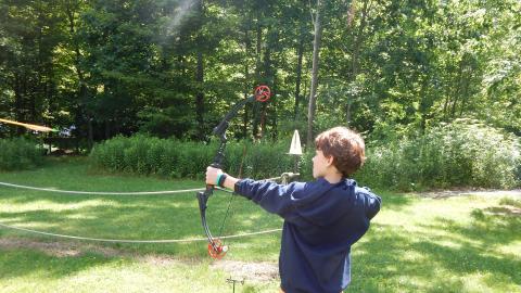 Youth facing away from the camera with bow drawn.