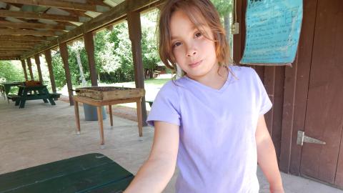Youth holds out her arm to show a moth resting there.