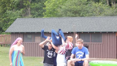 Youth hoist another in a blue suit up onto their shoulders.