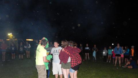 CIT Director awards t-shirts to campers completing their CIT III week of training at campfire.