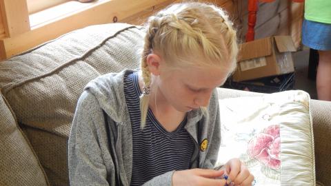 Camper sitting on couch working on a boondoggle.