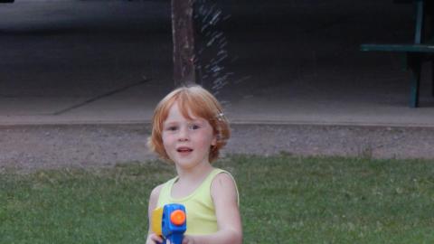 Youth pointing water gun at camera.