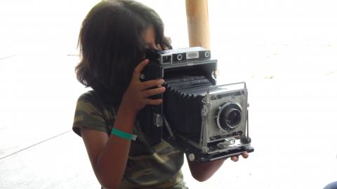 camper holding an old fashioned camera and looking through the lens.
