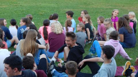 Campers seated on the lawn chatting.