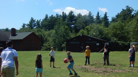 Youth holding a ball in a circle of others.