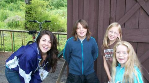 Counselor and three youth stand together smiling at the camera.