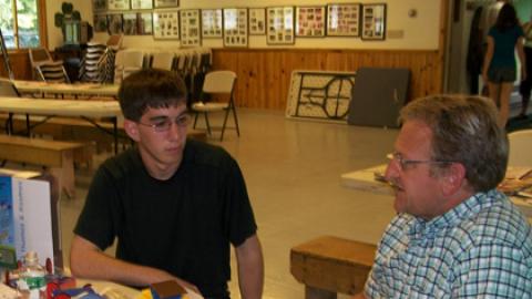 counselor and camp administrator sit together reviewing materials for a renewable energy class/activity.