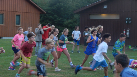 Youth running and smiling during a large group game in the field.