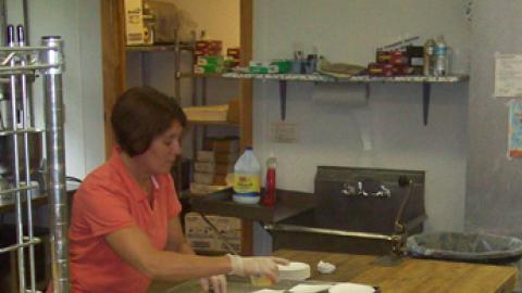Head cook cuts and plates birthday cake for an evening snack.