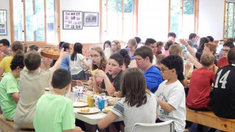 Campers and counselors seated together for a family style meal.