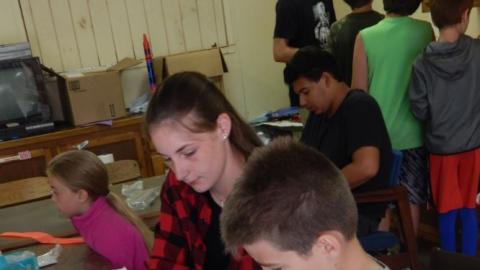 Camper working with CIT III to build a model rocket kit.