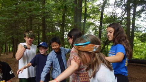 Youth balancing on a wooden platform in the woods.
