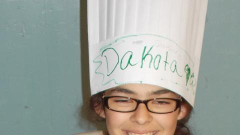 camper holding culinary creation wearing chef's hat