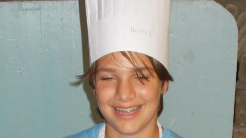 camper holding culinary creation wearing chef's hat