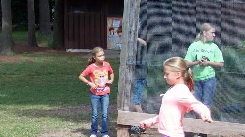 camper kicking kickball with three campers watching in the background