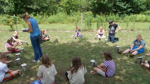 counselor helping campers cook outdoors using coffee cans