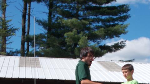 camper launching model rocket with campers watching in the background 