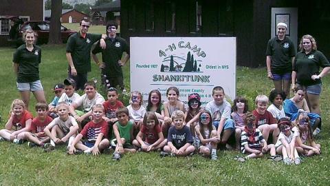 campers sitting in front of Camp Shankitunk sign with counselors standing in back 