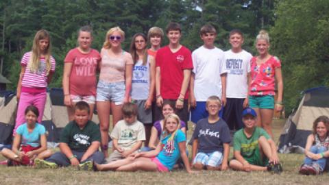 Youth sitting for a photo with others standing in the background. 