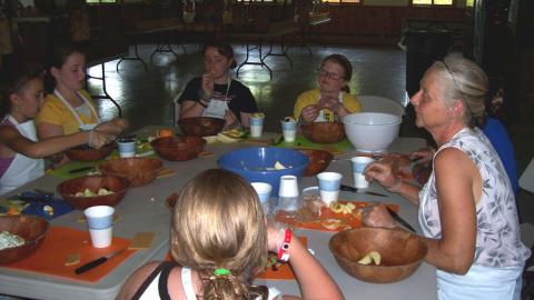 Youth seated around the table with CCE Educator tasting sliced fruits/veggies.