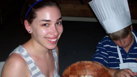 Smiling staff  holds up a bowl of yogurt with mixed fruit in it.