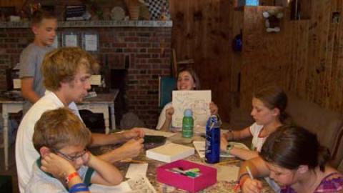 Youth seated around a table drawing and looking at newspapers.