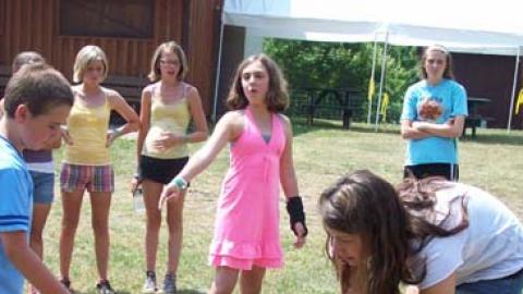 Youth preparing to drop mentos into bottle of coke. Classmates stand aside watching.