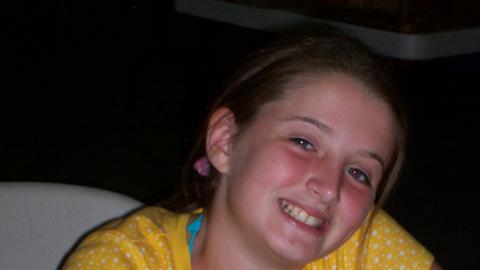 Youth smiling and eating a snack.