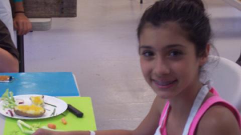 Smiling youth cuts vegetables. 