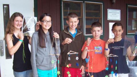 5 youth in front of dining hall holding mobiles.
