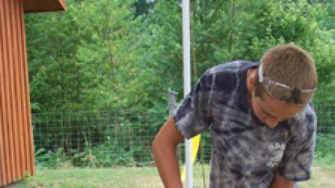 youth using a drill to assemble pieces of an Adirondack chair.