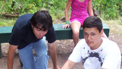 Two staff build a tee-pee style fire in pit.